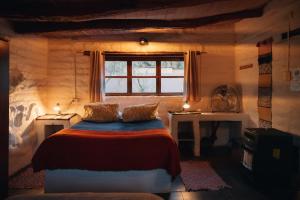 a bedroom with a bed and a window and two tables at CaminAndes Hostal in San Pedro de Atacama