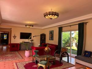 a living room with red furniture and a chandelier at Villa Essalah & Spa Marrakech in Marrakesh