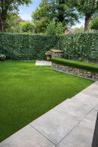a garden with green grass and a stone wall at Spacious 2 Bed Apartment with Free Parking, Sleeps Up To 6 in Purley