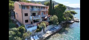 a house on a cliff next to the water at Apartmani Nikoletić in Klek