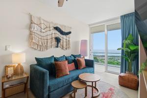 a living room with a blue couch and a large window at Ocean View Haven Walk to Beach Private Rooftop Terrace in Akumal
