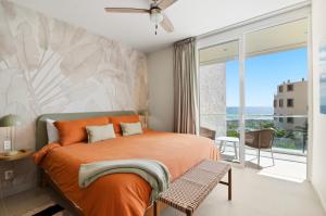 a bedroom with an orange bed and a balcony at Ocean View Haven Walk to Beach Private Rooftop Terrace in Akumal