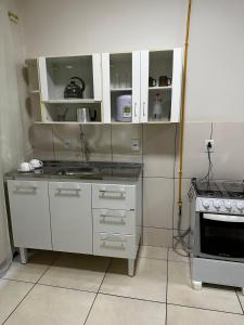 a kitchen with white cabinets and a sink and a stove at Apt Aconchegante no Centro de Rolim in Rolim de Moura +53 photos