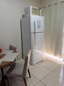 a white refrigerator in a kitchen with a table and a chair at Apt Aconchegante no Centro de Rolim in Rolim de Moura