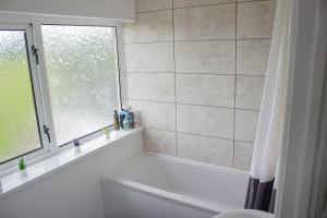 a white bath tub in a bathroom with a window at 3-bedroom pet friendly home with off road parking in Swansea +53 photos