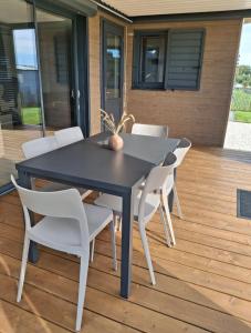 a black dining table and white chairs on a deck at Chalet in Gouesnach