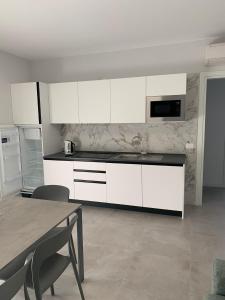 a kitchen with white cabinets and a table with chairs at Matilde Apartments Caorle in Caorle