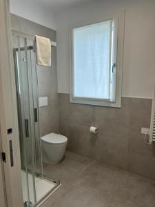 a bathroom with a shower and a toilet and a window at Matilde Apartments Caorle in Caorle +13 photos