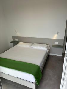a bedroom with a white bed with a green blanket at Matilde Apartments Caorle in Caorle