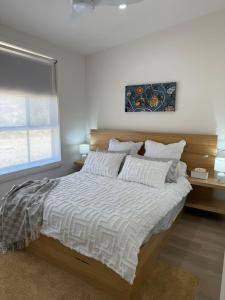 a bedroom with a large bed with white sheets and a window at Banksia apartment - Escape to Serene Rural Bliss! in Inverell