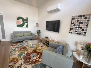 a living room with two couches and a tv at Banksia apartment - Escape to Serene Rural Bliss! in Inverell