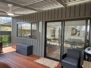 a screened in porch with a chair and sliding glass doors at Banksia apartment - Escape to Serene Rural Bliss! in Inverell