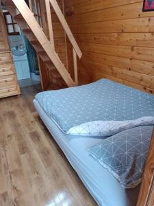 a bed in a room with a wooden wall at Domki PIĘKNY WIDOK górne - Solina Centrum in Solina