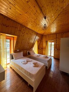 two beds in a room with a wooden ceiling at The White Troy in Sarandë