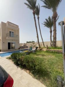 a house with palm trees and a swimming pool at Maison des 5 palmiers in Taguermess