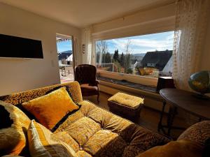 a living room with a couch and a large window at Panorama Joy - stilvolle Gemütlichkeit mit Weitblick in Schmallenberg