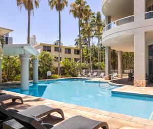 a swimming pool with lounge chairs next to a building at Oaks Gold Coast Hotel in Gold Coast