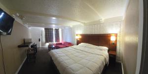 a hotel room with a large bed and a red chair at Exceed Inn Indianapolis Airport South in Indianapolis +19 photos