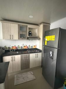 a kitchen with a stainless steel refrigerator and wooden cabinets at En el corazon de Dosquebradas in Dosquebradas
