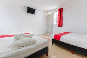 a bedroom with two beds and a window with a red curtain at HOTEL LOS CEDROs in Yalsí
