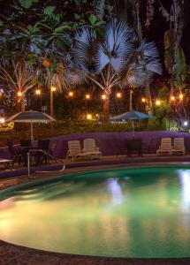 a swimming pool with chairs and umbrellas at night at Las Palomas Villas in Cocles