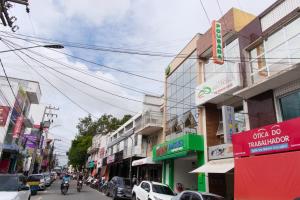 a busy city street with parked cars and buildings at Pousada Vasconcelos Tianguá in Tianguá