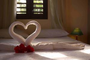 a bed with two swans making a heart on it at Pousada Sol e Luna - Pipa Garden in Pipa