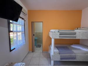a bedroom with a bunk bed and a bathroom at Recanto Aconchego Itapoá in Itapoa