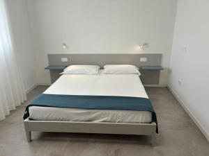a bedroom with a bed with white sheets and pillows at Matilde Apartments Caorle in Caorle