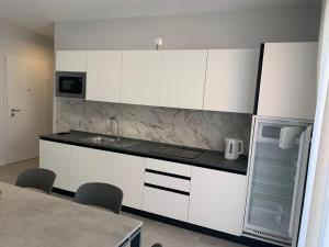 a kitchen with white cabinets and a sink and a refrigerator at Matilde Apartments Caorle in Caorle