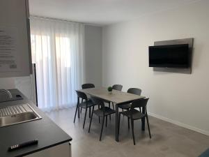 a kitchen with a table with chairs and a television at Matilde Apartments Caorle in Caorle