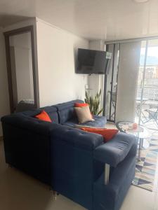 a blue couch with orange pillows in a living room at En el corazon de Dosquebradas in Dosquebradas