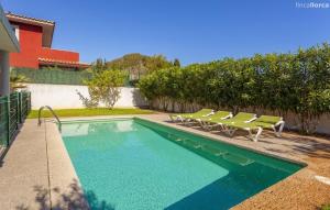 a swimming pool with lounge chairs next to a house at Oasis N'aguait in Cala Ratjada