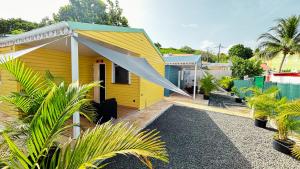 a yellow house with a white awning and some plants at Bungalow Soleil Sainte-Anne - Plage à pied in Sainte-Anne