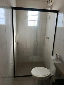 a bathroom with a toilet and a glass shower at Kitnet 1 quarto in Torres