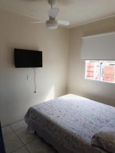 a bedroom with a bed and a flat screen tv at Kitnet 1 quarto in Torres