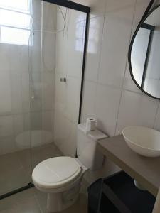 a white bathroom with a toilet and a sink at Kitnet 1 quarto in Torres