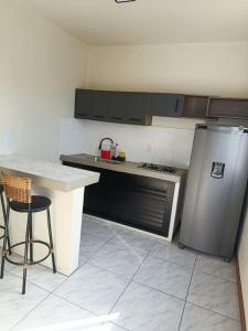 a kitchen with a counter and a refrigerator and a table at Kitnet 1 quarto in Torres
