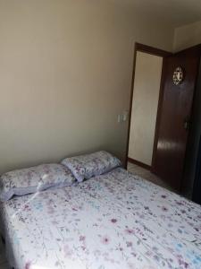 a bedroom with a bed with a floral comforter at Kitnet 1 quarto in Torres