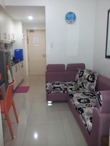 ein Wohnzimmer mit einem lila Sofa und einer Küche in der Unterkunft FinkSea @ Sea Residences in Manila