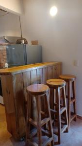 a kitchen with three wooden stools at a counter at Doña Mayra Aparta Hotel, Rustico in Las Terrenas +3 photos