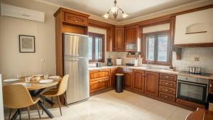 a kitchen with a table and a stainless steel refrigerator at Vignetta Mare 2BR Villa με Θέα & και Ιδιωτικό Πάρκινγκ in Ermoupoli