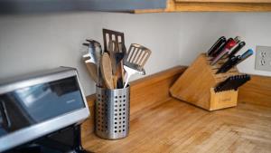 a metal container of utensils on a counter next to a microwave at Grizzly Grotto in Red Lodge