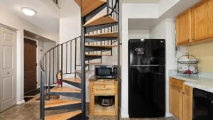 a spiral staircase in a kitchen with a black refrigerator at Sans Souci Cabin in Red Lodge
