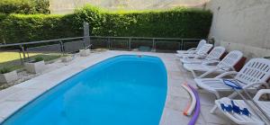a swimming pool with white chairs next to a fence at Chalet Nuevo Amanecer in Merlo