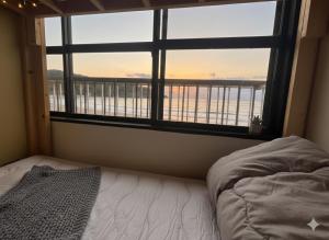 a bedroom with a bed and a large window at MACARA Guesthouse in Nichinan