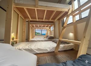 a bunk bed room with three bunk beds in it at MACARA Guesthouse in Nichinan