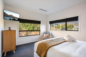 a bedroom with two windows and a bed with a chair at Blackwood Lakeview Retreat in Queenstown