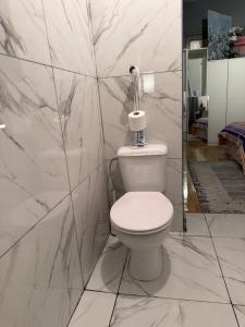 a white bathroom with a toilet and marble walls at Fly City châtelet in Châtelet