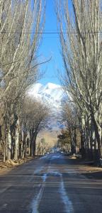 an empty road with a snow covered mountain in the background at Hospedaje J & L in Uspallata